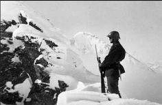 a man standing on top of a snow covered mountain with skis in his hands