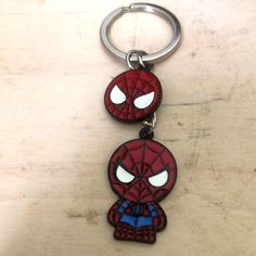 two spider - man key chains are sitting on a table