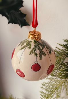 an ornament hanging from a christmas tree with holly and red berries on it