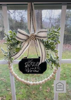 a wreath hanging on the side of a window with a sign that says, be still and know