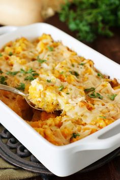 a white casserole dish filled with eggs and parsley on a wooden table