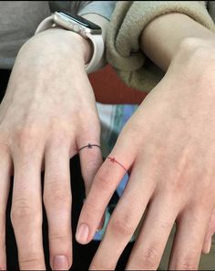 two people with rings on their fingers and one has a cross tattoo on the ring