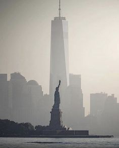 the statue of liberty is surrounded by fog and skyscrapers in new york city, ny