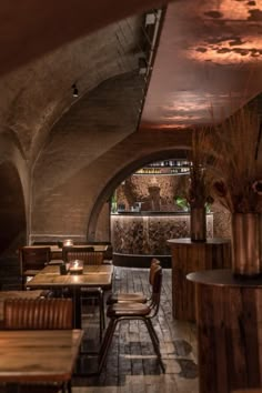 the inside of a restaurant with wooden tables and chairs, an arched ceiling and brick floor