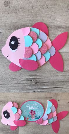 paper cut out fish with pink and blue colors on it's body, sitting on top of a wooden floor