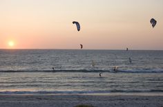 people parasailing in the ocean at sunset