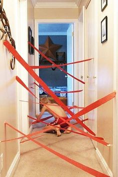 a young boy is playing with red tape in front of the door to his house