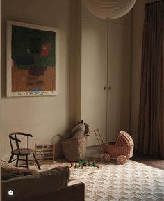 a baby's room with toys on the floor and a painting hanging above it