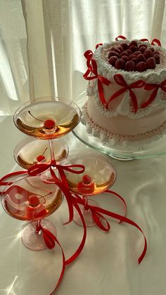 there are three desserts on the table with red ribbons around them and one has a heart shaped cake