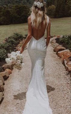 a woman in a white dress walking down a path