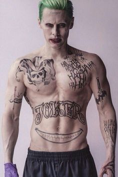 a man with green hair and tattoos on his chest