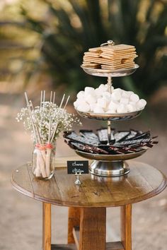 an assortment of desserts are displayed on a table with flowers and sticks in vases