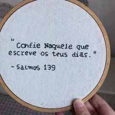 a person holding up a small embroidered piece with a quote on it that reads confite naquete que escreve os teus dias