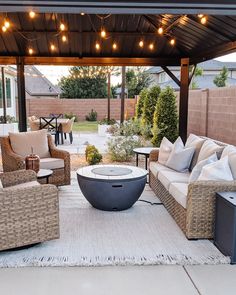 an outdoor living area with wicker furniture and string lights