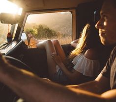 a man and woman sitting in the back of a truck with their feet on the dashboard