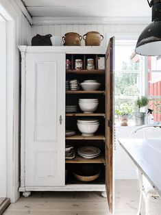 an open cabinet filled with dishes in a kitchen