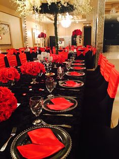 the table is set with black and red linens, silverware, and flowers