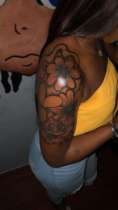 a woman with a flower tattoo on her arm and shoulder, next to a stuffed animal