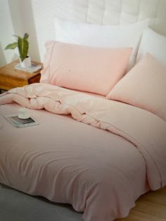 a bed with pink sheets and pillows on it