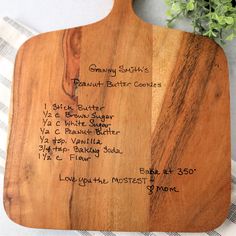 a wooden cutting board with writing on it and a potted plant in the background