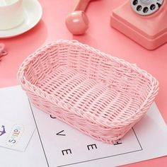 a pink basket sitting on top of a table next to a phone and other items