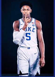 a male basketball player in a white uniform is holding his finger up to the side