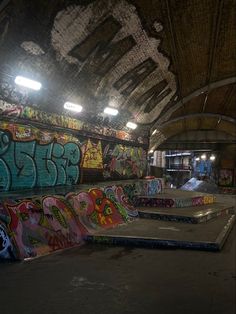 an indoor skate park with graffiti on the walls