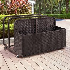 an outdoor storage box with wheels on a deck next to a swimming pool and shrubbery