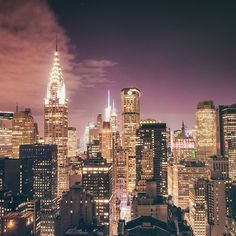 the city skyline is lit up at night, with skyscrapers in the foreground