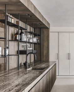 a kitchen with marble counter tops and wooden cabinets in the back drop off area, along with white cupboards