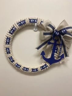 an anchor wreath with blue and white ribbon tied around it on a white wall background