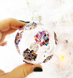 a hand holding a glass ornament with colorful sprinkles on it