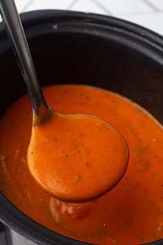 a spoon full of tomato soup in a pot