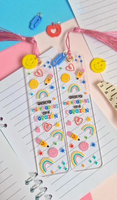 two bookmarks with rainbows and stars on them next to some writing paper, scissors and other items