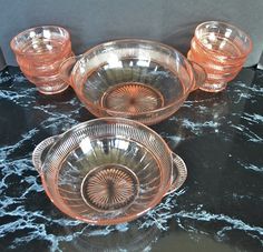 four pink glass dishes sitting on top of a marble countertop next to each other