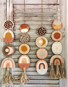 an assortment of plates hanging on a wall with tassels attached to the hooks