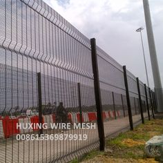 an image of people riding bikes on the road behind a wire mesh fence with red barriers