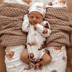 a baby wrapped in blankets laying on top of a bed