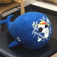 a blue stuffed animal with a pirate skull on it's head sitting on a black chair