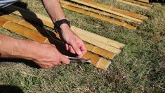 a man cutting bamboo strips with scissors on the ground in front of him and another person holding a pair of scissors next to them