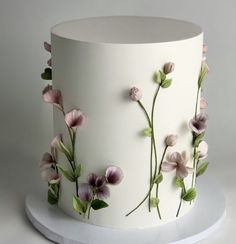 a white cake decorated with pink flowers and green leaves