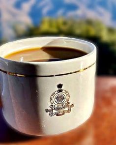 a cup of coffee sitting on top of a wooden table next to a mountain range