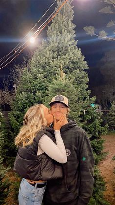 a man and woman kissing in front of a christmas tree