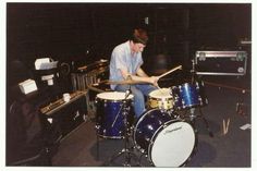 a man sitting on top of a drum set in front of a keyboard and drumstick