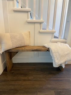 a wooden bench sitting in front of a stair case next to a banister with a white pillow on it