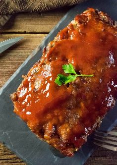 a piece of meatloaf on a plate with a fork and knife next to it