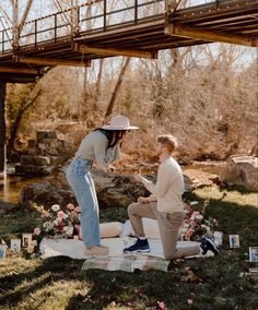 a woman kneeling down next to a boy on a blanket in front of a bridge