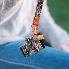 a person holding an orange and black camera strap