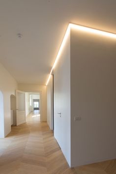 an empty room with white walls and wood floors is lit by led lighting on the wall