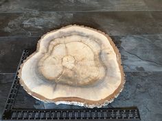 a piece of wood sitting on top of a metal grate next to a stone floor